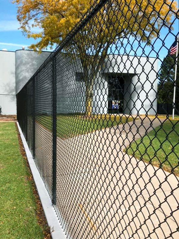 Black vinyl-coated chain link fence at a commercial property.