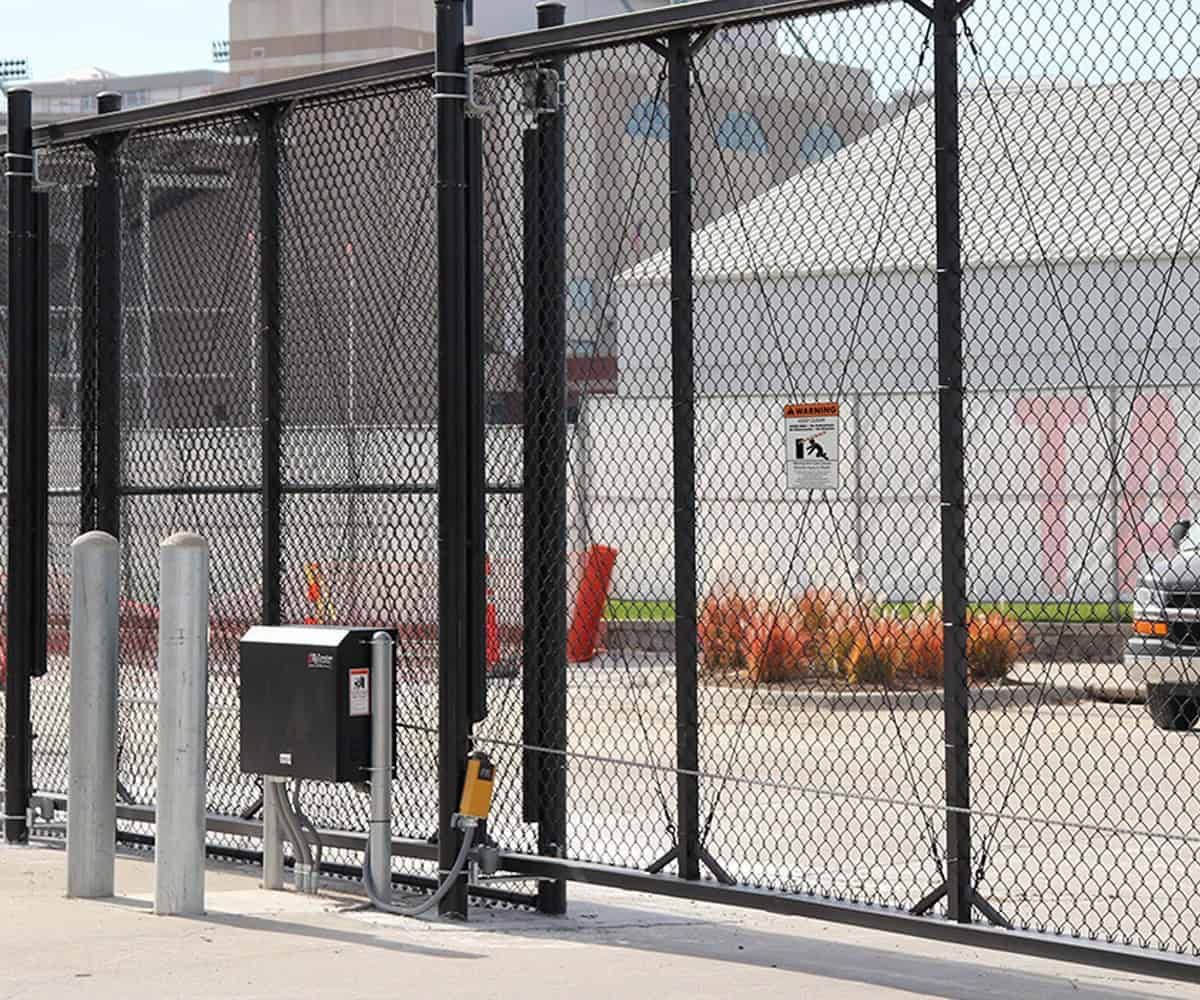 Large industrial cantilever slide gate with automated operator and bollards at a facility.