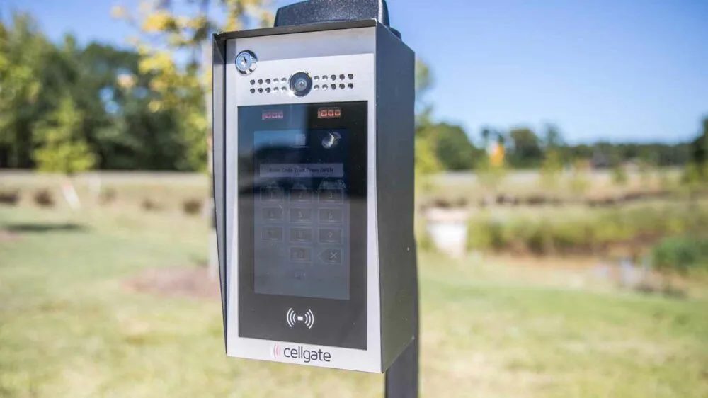 CellGate Watchman video intercom on a pedestal at a commercial gate entrance.